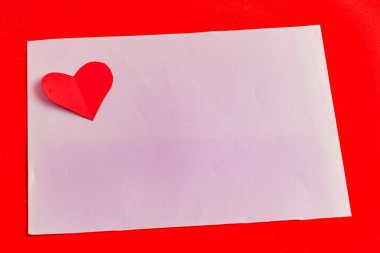 Parlak kırmızı bir zemin üzerinde mor bir yaprağın üzerinde kağıt bir kalple yazılmış bir aşk notu..