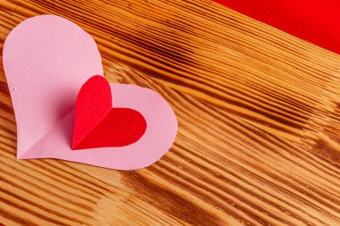 Büyük pembe ve küçük kırmızı kağıt kalpler ahşap bir tahta üzerinde kırmızı arka planda yüksek kaliteli fotoğraf.