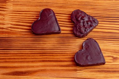 Tahta arka planda koyu çikolatadan yapılmış üç kalp. Kutlama konsepti. Yüksek kaliteli fotoğraf..