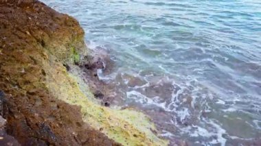 Huzurlu Kıyı Suları 'nda Rocky Shoreline ve Tranquil' in oynadığı Dalgalar görülüyor. Yüksek kalite 4k görüntü