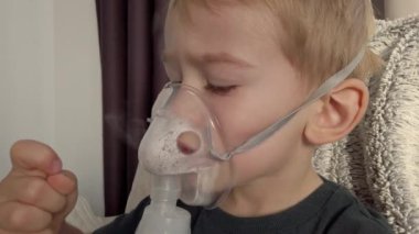 Sıcak ve rahat bir ev ortamında konforlu bir konumda iken nebulizör tedavisi gören bir çocuk