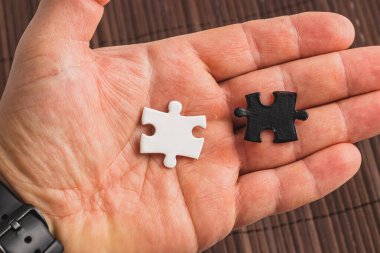 İki yapboz parçasını tutan bir el. Biri beyaz, biri siyah, zor seçim. Yüksek kalite fotoğraf..