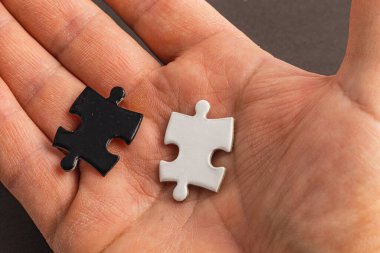 İki yapboz parçasını tutan bir el. Biri beyaz, biri siyah, zor seçim. Yüksek kalite fotoğraf..