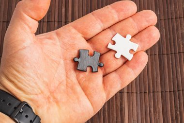 İki yapboz parçasını tutan bir el. Biri beyaz, biri siyah, zor seçim. Yüksek kalite fotoğraf..