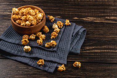 Atıştırmalık konsepti, ahşap bir kasede karamelleştirilmiş patlamış mısır, ahşap arka planda yüksek kaliteli fotoğraf.