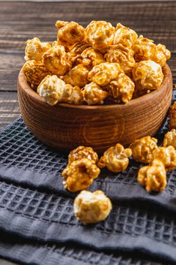Atıştırmalık konsepti, tatlı karamelize patlamış mısır gri, ahşap arka planda bir kasede yüksek kaliteli fotoğraf..