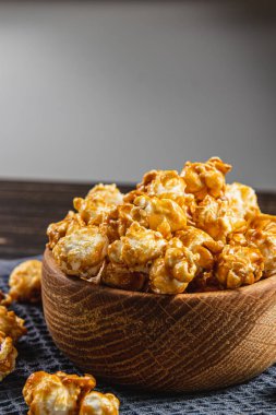 Atıştırmalık konsepti, ahşap bir kasede karamelleştirilmiş patlamış mısır, ahşap arka planda yüksek kaliteli fotoğraf.