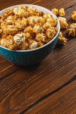 Atıştırmalık konsepti, tatlı karamelize patlamış mısır gri, ahşap arka planda bir kasede yüksek kaliteli fotoğraf..
