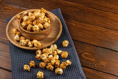 Tahta bir kasede karamelleştirilmiş patlamış mısır ve ahşap arka planda bir tabak yüksek kaliteli fotoğraf..