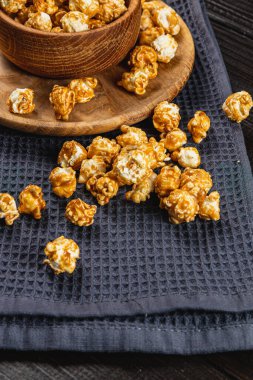 Tahta bir kasede karamelleştirilmiş patlamış mısır ve ahşap arka planda bir tabak yüksek kaliteli fotoğraf..