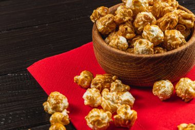 Atıştırmalık, film konsepti, kırmızı peçeteli ahşap bir kasede karamelize patlamış mısır..