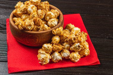 Atıştırmalık, film konsepti, kırmızı peçeteli ahşap bir kasede karamelize patlamış mısır..