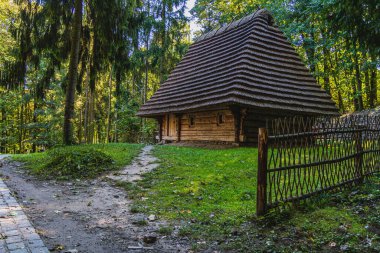 Parkta sazdan çatılı, büyüleyici bir ahşap ev keşfedin. Antika sergiler ve sakin bir gölet, yemyeşil ortamın ortasındaki yerel tarih ve kültüre bir bakış sunuyor..