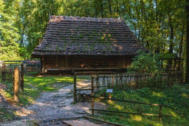 Ziyaretçiler, geleneksel sazdan çatılı ve çevresi yeşilliklerle çevrili, zengin antikalar ve miras bölgelerinin keşfini teşvik eden yerel bir tarih müzesine doğru yürüyorlar..