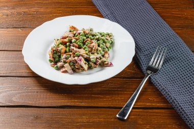 Canlı bir yemek, doğranmış soğan ve soğanla karıştırılmış yeşil bezelye içerir. Tam tahıllı ekmek, bu taze ve sağlıklı yemeğe eşlik eder. Köy ahşap bir masada basit tatlar sergiler..