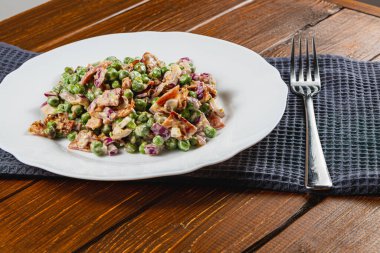 Canlı yeşil bezelyeler çıtır çıtır soğanlar ve mor soğan ile karıştırılır ve bir dilim tam tahıllı ekmeğin üzerinde servis edilir. Bu yemek taze malzemelerin ve sağlıklı beslenmenin özünü yakalar..