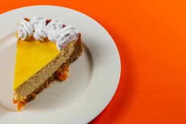 Taze yapılmış portakallı cheesecake, kremalı girdaplarla kaplı bir tabakta oturur ve rahatlatıcı bir öğleden sonrası için mükemmel aromatik bir fincan espresso ile birlikte eğlenmeye hazırdır..