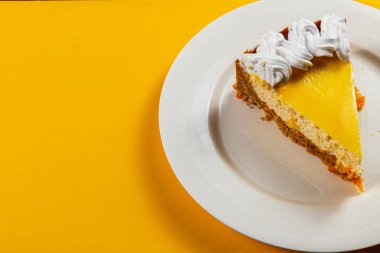 Lezzetli bir dilim ev yapımı portakallı cheesecake aromatik espressonun yanında parlak bir tabakta duruyor. Mükemmel dengeli tatlar, tatmak için cazip bir tatlı deneyimi yaratır..