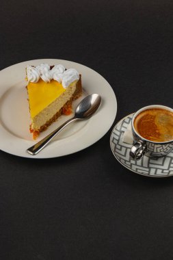 A slice of fresh homemade orange cheesecake sits elegantly on a white plate, paired with a rich cup of aromatic espresso. clipart