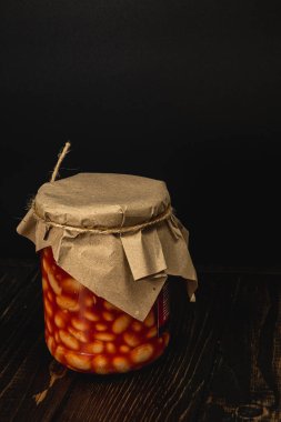 Fasulye turşusuyla dolu cam bir kavanoz domuz yağı kaplı kapakla mühürlenir. Köy ambalajı cazibe katıyor, bu da onu her kilere mükemmel bir katkı yapıyor. Bu ev yapımı ikram korunmak için idealdir..