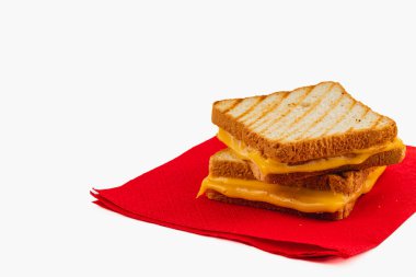 This grilled cheese sandwich showcases layers of melted cheddar cheese between two slices of perfectly toasted bread. Set on a red napkin, it is ready for a delicious bite at any mealtime. clipart