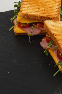 Savor a homemade grilled cheese sandwich featuring layers of ham, fresh spinach, arugula, and juicy tomatoes on toasted bread, perfect for lunch or a quick snack. clipart