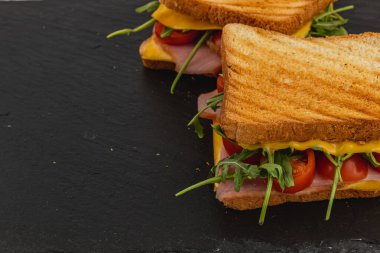 Jambon, taze ıspanak, roka ve domatesle dolu leziz bir ızgara peynirli sandviçin tadını çıkarıyorum..