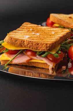 Lezzetli ızgara bir sandviçe katmanlar dolusu jambon, erimiş peynir, taze domates, roka ve kızarmış ekmek üzerine ıspanak eklenir. Atıştırmalık ya da kahvaltı için mükemmel..