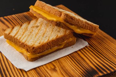 Bu ızgara peynirli sandviç mükemmel kızarmış ekmek dilimlerinin arasında yapışkan erimiş peynir içeriyor. Tahta bir tabakta sıcak servis edilir, mükemmel bir brunch ya da öğle yemeği olur..