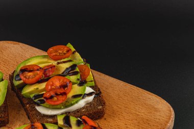 Dilimlenmiş avokado ve balzamik jöleli kiraz domatesli taze yapılmış tost. Doğal ışıklandırmayla evde rahatlatıcı bir kahvaltı yaparken eğlendim..