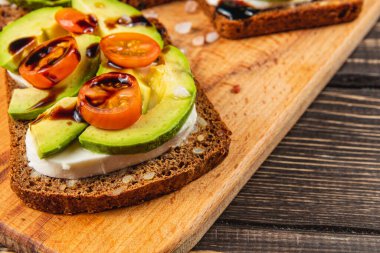 İçinde taze avokado ve vişneli domateslerin olduğu canlı bir yemek. Bu sağlıklı tost kremalı peynirle hazırlandı ve lezzetli bir sos serpiştirildi..