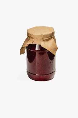 Ev yapımı kiraz ve ahududu reçeli ile dolu büyük bir kavanoz kırsal bir kağıt kapakla kaplıdır. Canlı kırmızı renk içinizdeki tatlılığa işaret eder. Yıl boyunca eğlenmek için mükemmeldir..