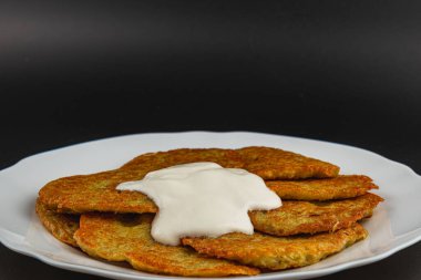 Altın sarısı patates krepleri beyaz bir tabakta güzelce sıralanmış, üzerinde bol kremalı sos var. Atıştırmalık ya da aperatif için ideal, her toplanma için mükemmel..