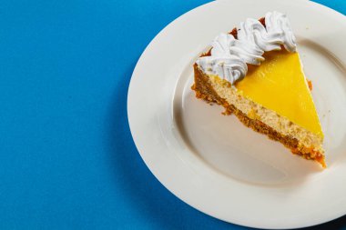 Taze yapılmış bir dilim turuncu peynirli kekin tadını çıkar, kremayla kaplı, aromatik espresso ile mükemmel eşleştirilmiş. Bu lezzetli ikram günün her saatinde rahatlamaya ve hoşgörüye davet ediyor..