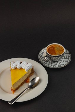 Lezzetli bir dilim portakallı cheesecake 'in üstüne krem şanti konmuş sıcak bir öğleden sonra espresso ile mükemmel bir şekilde eşleştirilmiş..