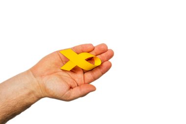 Bir el sarı bir kurdele tutar, kanseri temsil eden desteği ve farkındalığı sembolize eder. Arkaplan, hastalığa karşı umut ve dayanışma mesajını vurgulayan açık..