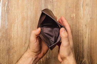 Elinde boş bir deri cüzdan tutan bir adam, ekonomik zorlukların ve krizin ortasında çözüm arayışının katıksız gerçekliğini gösteriyor. Kırsal arkaplan anın altını çizer.