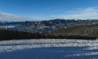 Polyanytsia, Ukrayna 'daki parlak mavi gökyüzünün altındaki karla kaplı dağların manzarası. Bu kış manzarası 2025 Ocak 'ında doğanın dingin güzelliğini yansıtıyor..