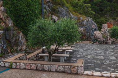 Huzurlu bir alanda, yemyeşil ve kayalık kayalıklarla çevrili taştan yapılmış kırsal banklar yer alıyor. Doğanın sosyalleşmesi ya da eğlenmesi için ideal olan bu nokta, rahatlamaya davetiye çıkarır..