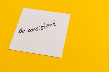 Basit bir beyaz yapışkan not kalın bir el yazısı ile tutarlı bir ifade gösterir. Not, parlak sarı bir zemin üzerinde keskin bir tezat oluşturarak olumlu bir titreşim uyandırıyor..