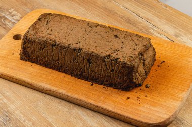 Ev yapımı tavuk ciğeri ezmesi, ahşap bir kesme tahtasının üzerinde, zengin rengini ve dokusunu sergiliyor. Bu lezzet, toplantılarda kabuklu ekmeğe bulaşmak için mükemmeldir..