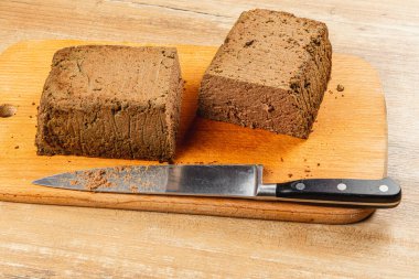 İki blok zengin, ev yapımı tavuk ciğeri ezmesi keskin bir bıçağın yanında, kızarmış ekmek veya krakerlerin üzerine yayılmak için harika bir tahta üzerinde sergileniyor..