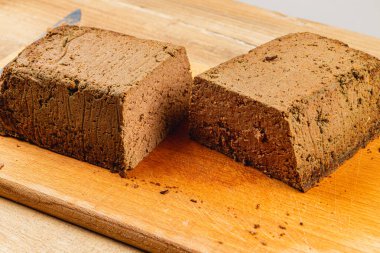 Taze yapılmış tavuk ciğeri ezmesi, mükemmel dilimlenmiş ve ahşap bir kesme tahtasında sunuluyor. Bu yemek, aperatifler veya yayılımlar için ideal pürüzsüz bir doku ve zengin bir renk sergiler..