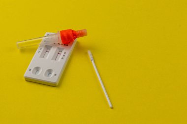 Hızlı bir test kiti parlak sarı bir yüzeye dayanır, içinde küçük bir şişe ve bir çubuk bulunur. Hızlı ve etkili sağlık testleri için tasarlanmıştır, ev kullanımına uygundur..