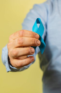 Bir insan prostat kanserine karşı verilen savaşı sembolize eden mavi bir farkındalık kurdelesi taşıyor. Bu eylem erkek sağlığına destek veriyor ve kanser önleme ve farkındalığın önemini vurguluyor.