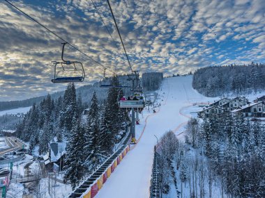 Polyanytsia Ukrayna 18.01.25 kayakçı etrafında büyüleyici karlı bir manzara bulunan bir teleferik yolculuğunun keyfini çıkarırlar. Sahne, macera ve doğal güzelliklerle dolu bir kış gününü yakalar..