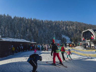 Poliyanytsia Ukrayna 18.01.25 Kayakçı ve snowboardculardan oluşan büyük bir kalabalık açık bir kış gününde karla kaplı ağaçlarla çevrili bir kayak merkezinde kuyruğa girer.