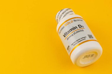 24.03.25 Lviv Ukrayna Bir şişe D3 vitamini parlak sarı zemin üzerine yerleştirilir. Bu temel besin, genel sağlık ve refahı destekler..