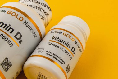 24.03.25 Lviv Ukrayna Parlak sarı bir yüzey üzerinde vitamin D3 şişelerinin yer aldığı diyet takviyelerinin yakın görüntüsü, sağlığın ve beslenmenin önemini vurguluyor.