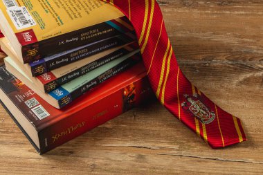 25.03.25 Lviv Ukrayna. Harry Potter kitaplarının renkli bir koleksiyonu, kırmızı ve sarı çizgili bir kravatla birlikte ahşap bir masanın üzerinde duruyor..